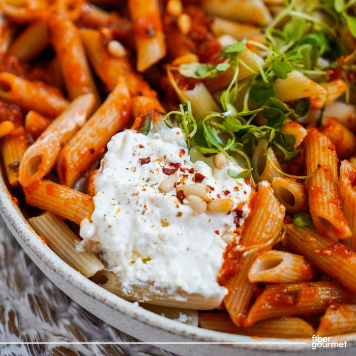 Fiber Gourmet penne in tomato sauce topped with ricotta, pine nuts and microgreens