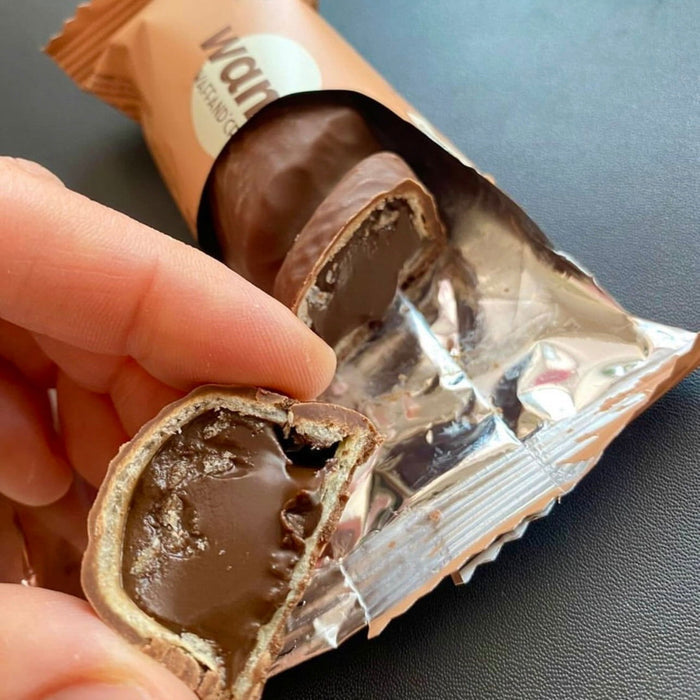 WANA Waffand'Cream protein bar split open in hand, showing soft dark cream filling and waffle layers